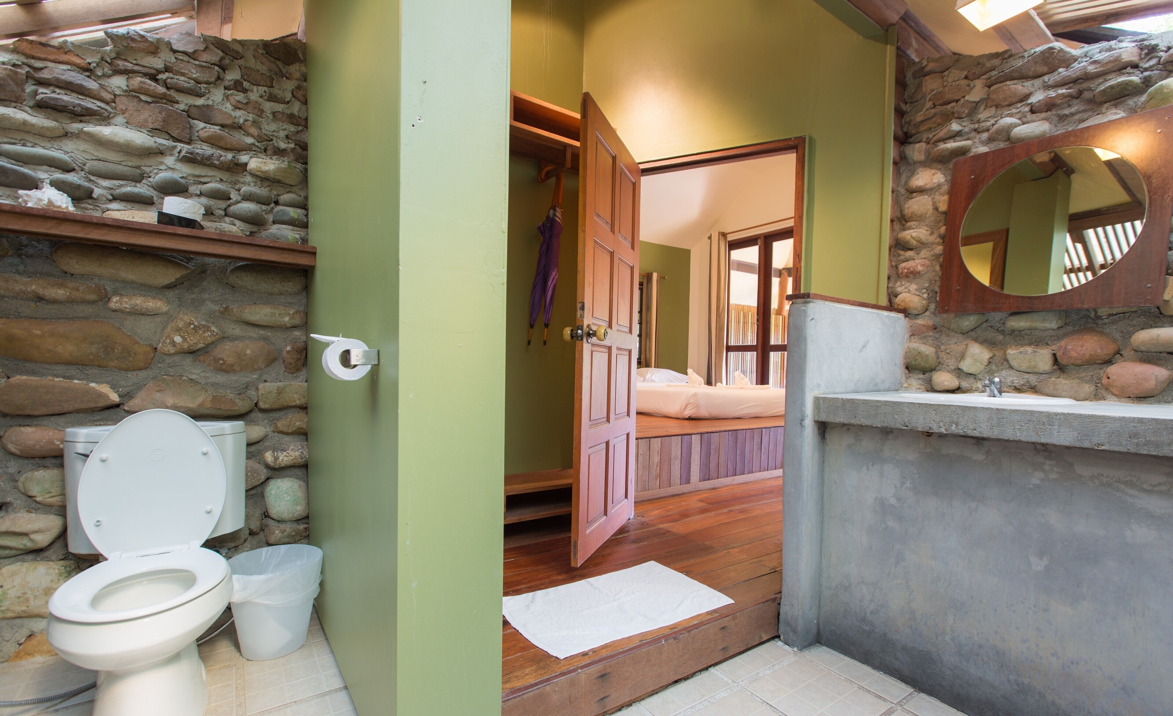 A bathroom with a stone wall, a wooden door, a sink, and a toilet.