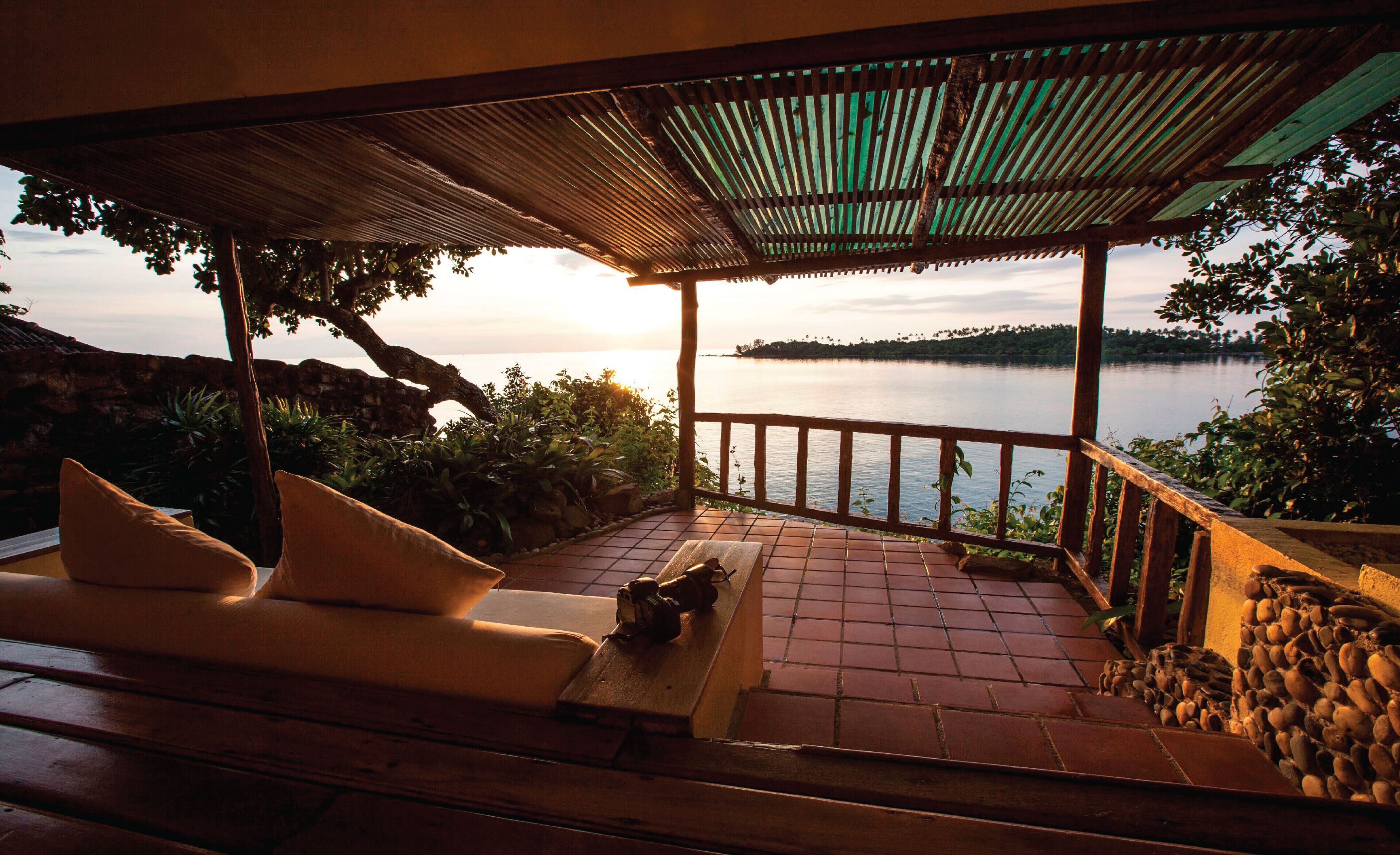 Un área de estar al aire libre techada con vistas a un lago y tierras lejanas.