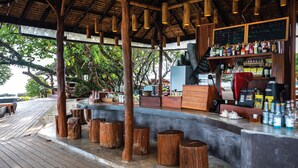 Un área de bar al aire libre con taburetes de madera, una barra y una máquina de café.