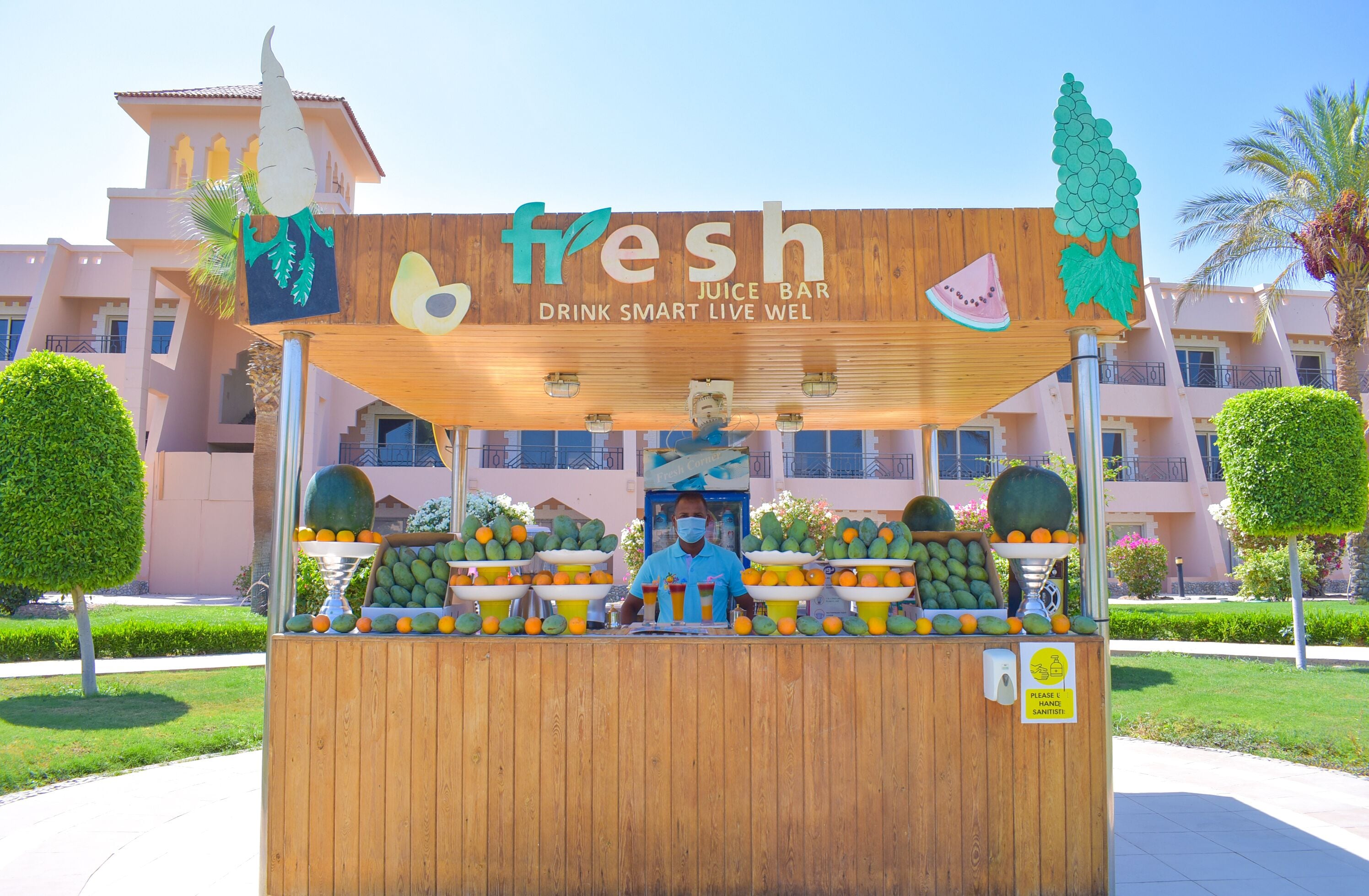A juice bar named 'fresh' with a wooden structure, a signboard, and a variety of fruits displayed.
