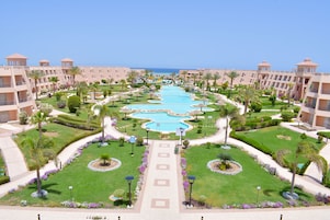A resort with multiple swimming pools, palm trees, and a clear view of the ocean.