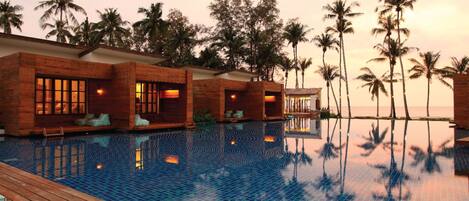 Un resort con piscina, terraza de madera y palmeras.