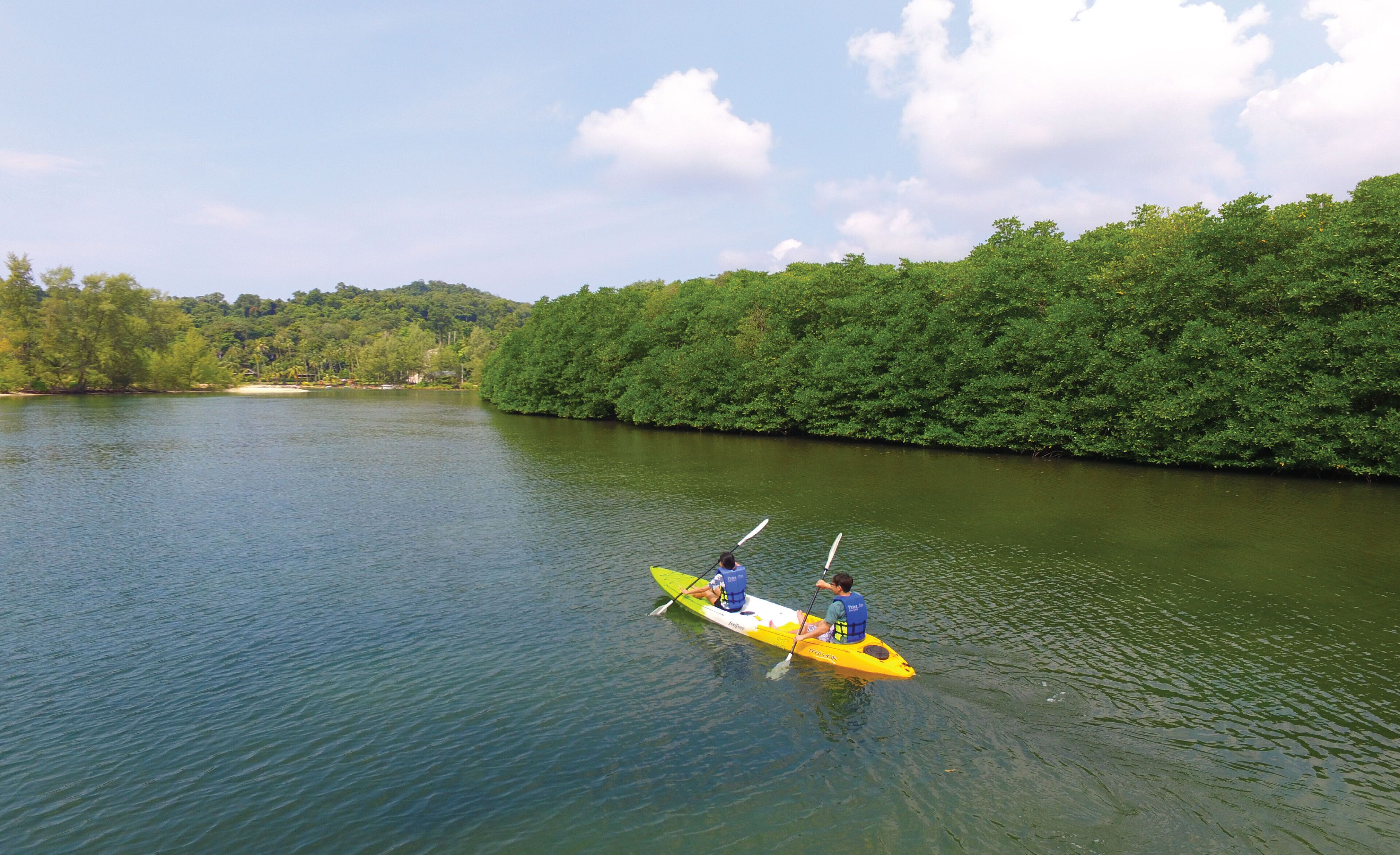 A river with a kayak and two people paddling.