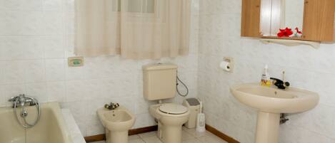 A bathroom with a bathtub, toilet, bidet, and sink.