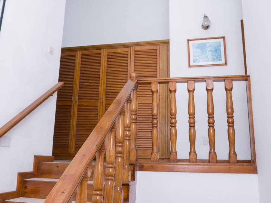 A wooden staircase with a handrail and a wooden railing with balusters.