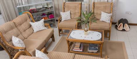 A living room with striped sofas, a coffee table with books, and a glass display cabinet.