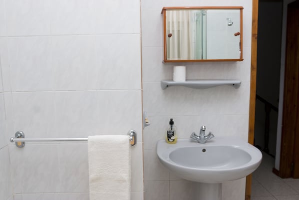 Un baño con un lavabo blanco, un espejo y un perchero para toallas.