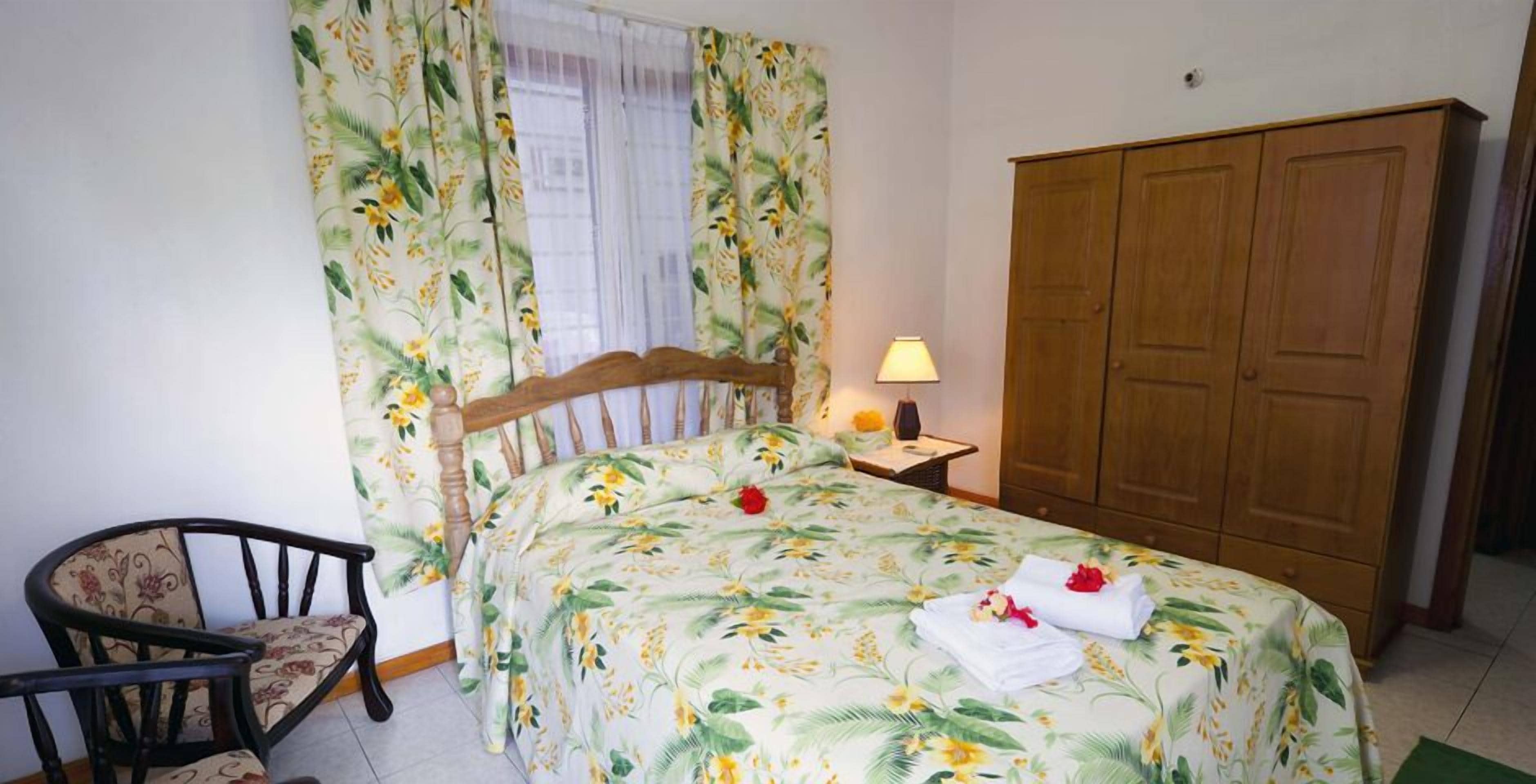 Un dormitorio con cama, una silla, mesita de noche con lámpara y armario.