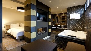 A modern hotel room with a bed, a fireplace, a sitting area, and a bathroom with a bathtub and sink. - 't Goude Hooft (The Hague)