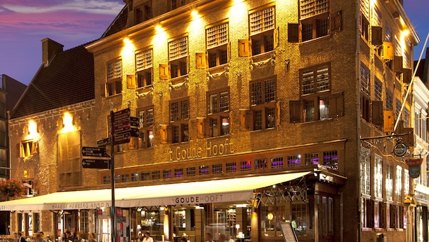 A historic building with multiple windows and a cafe area with outdoor seating. - 't Goude Hooft (The Hague)