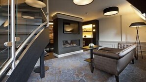A modern interior with a staircase, a fireplace, a sofa, and a floor lamp. - 't Goude Hooft (The Hague)