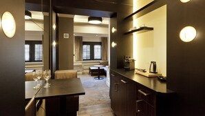 A modern hotel room with a dining area, a kitchen with a coffee machine, and a seating area with a view of the outside. - 't Goude Hooft (The Hague)