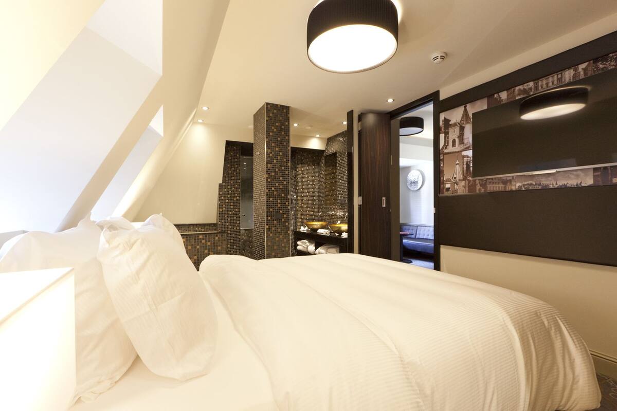 Une chambre à coucher moderne avec un grand lit, une coiffeuse intégrée avec un miroir et un téléviseur fixé au mur.