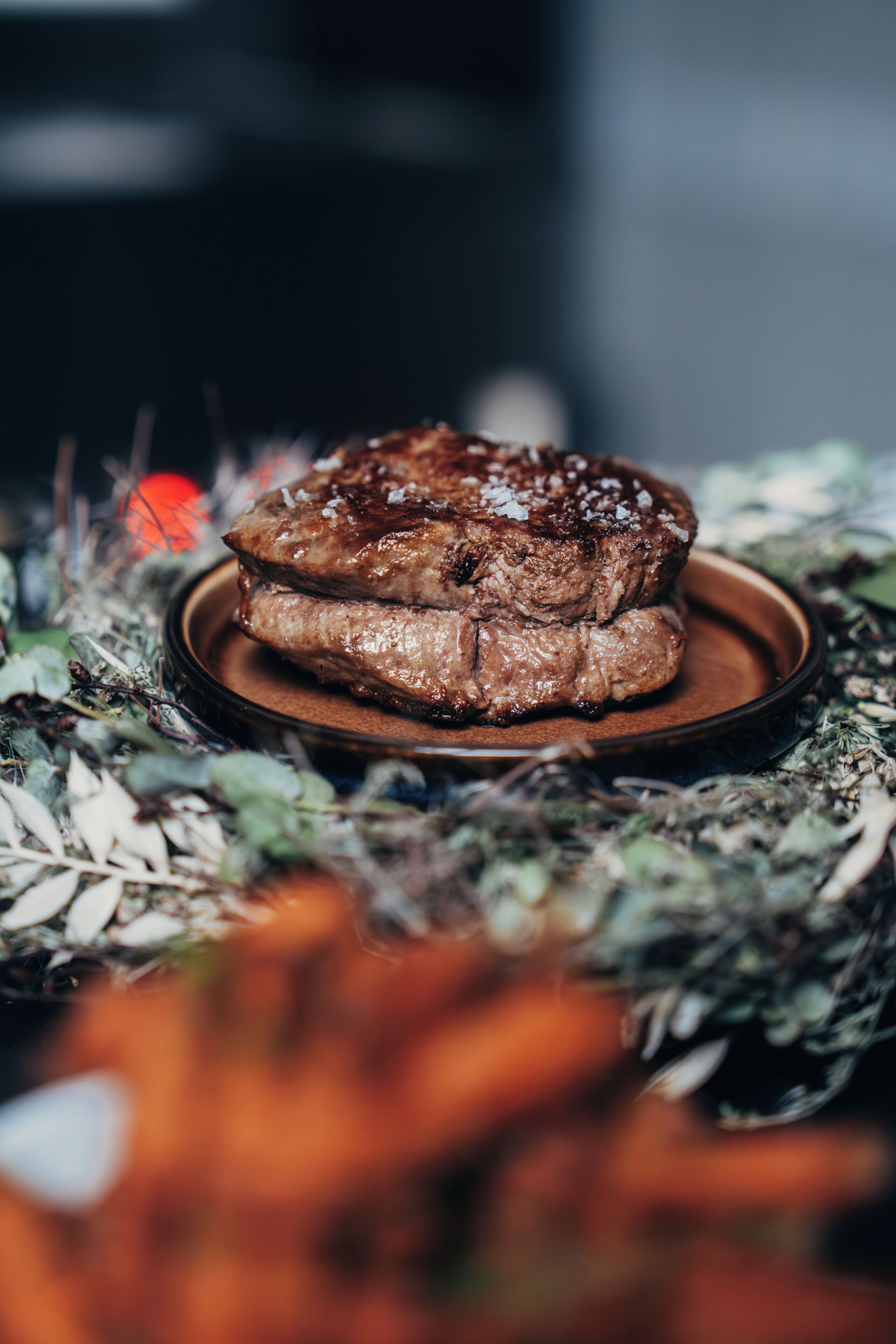 Un bistec en un plato sobre un fondo desenfocado.
