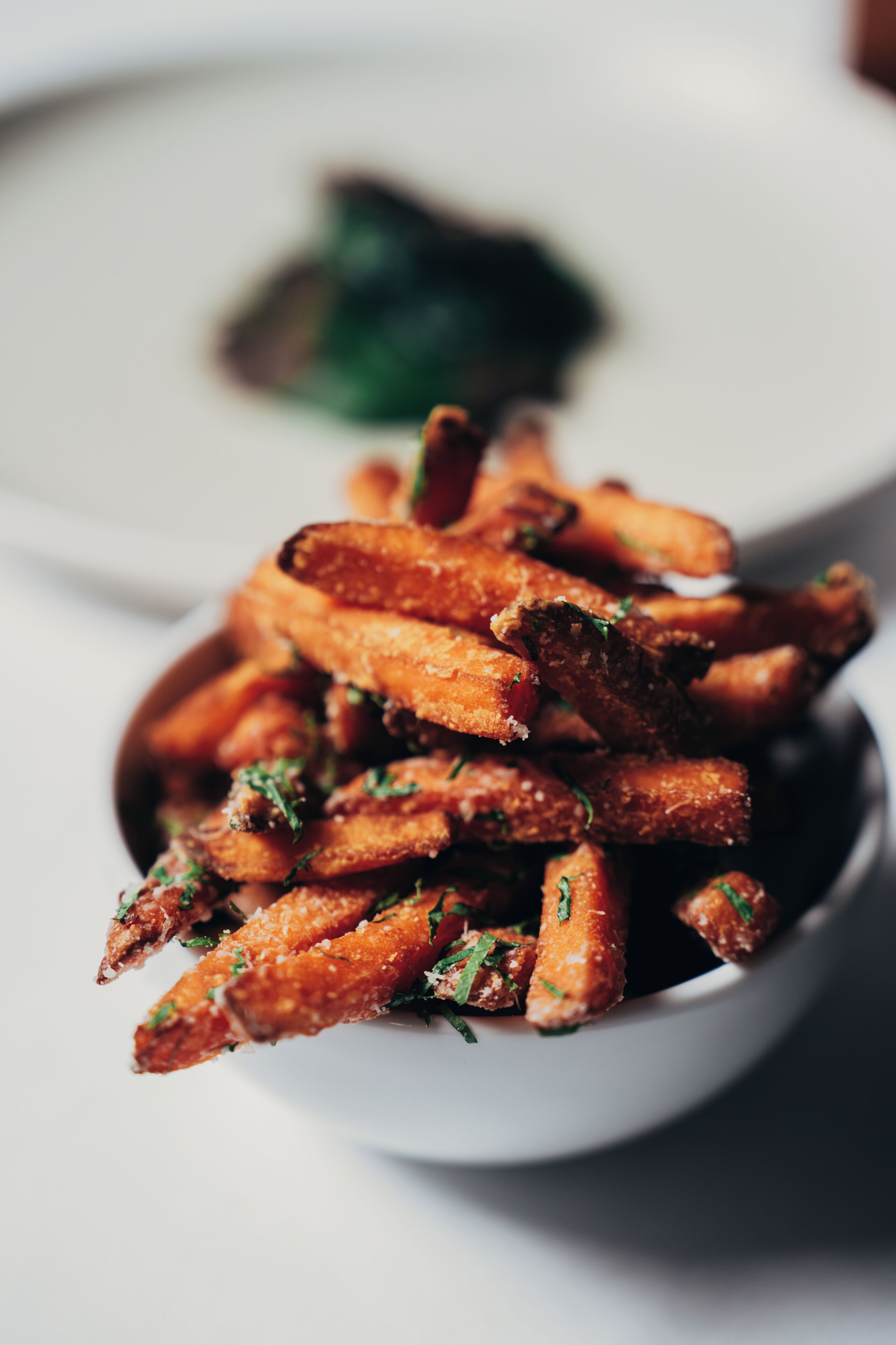 Un bol de papas fritas crujientes, sazonadas y adornadas con hierbas.