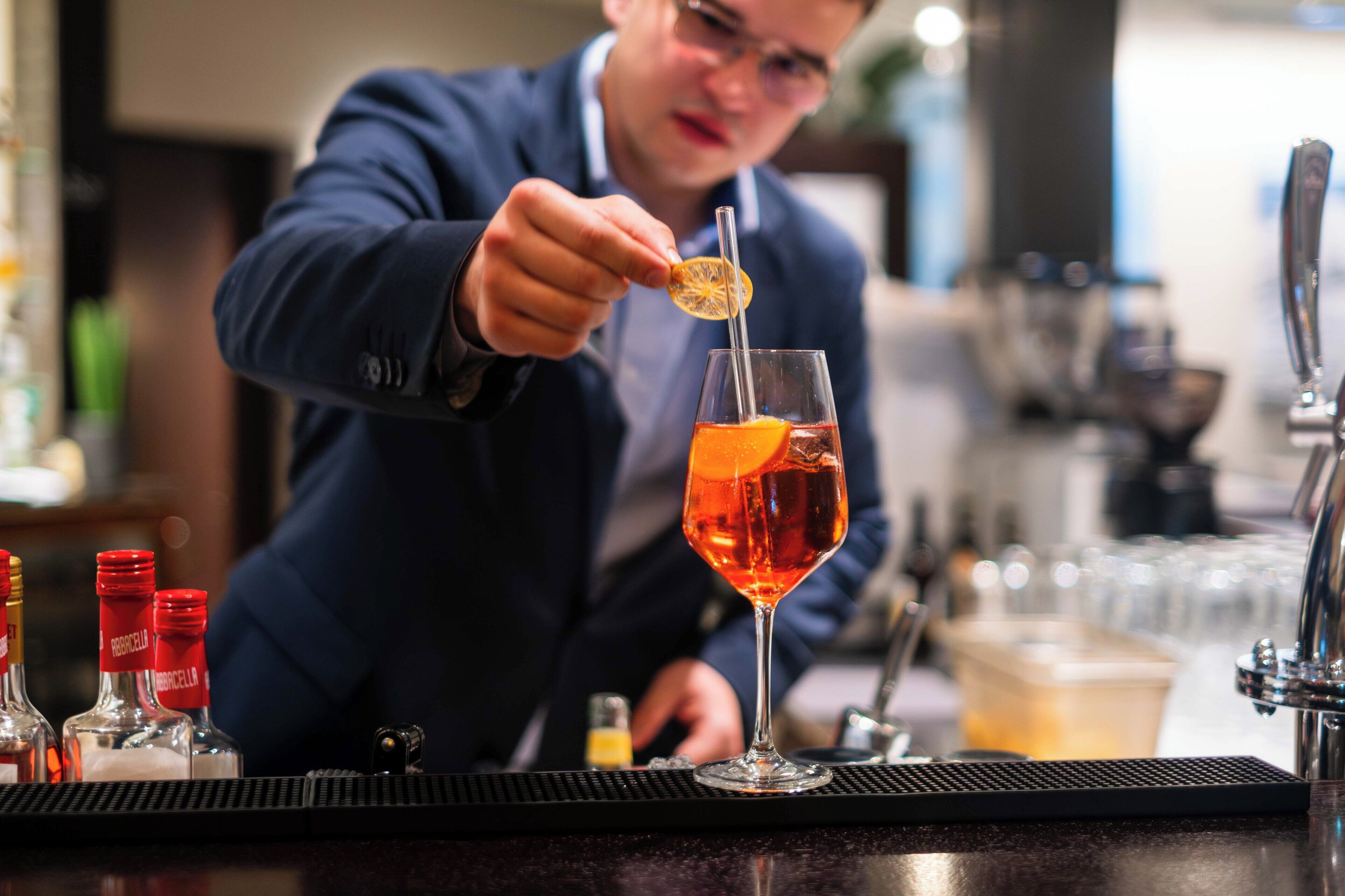 A bartender preparing a cocktail with a citrus garnish.