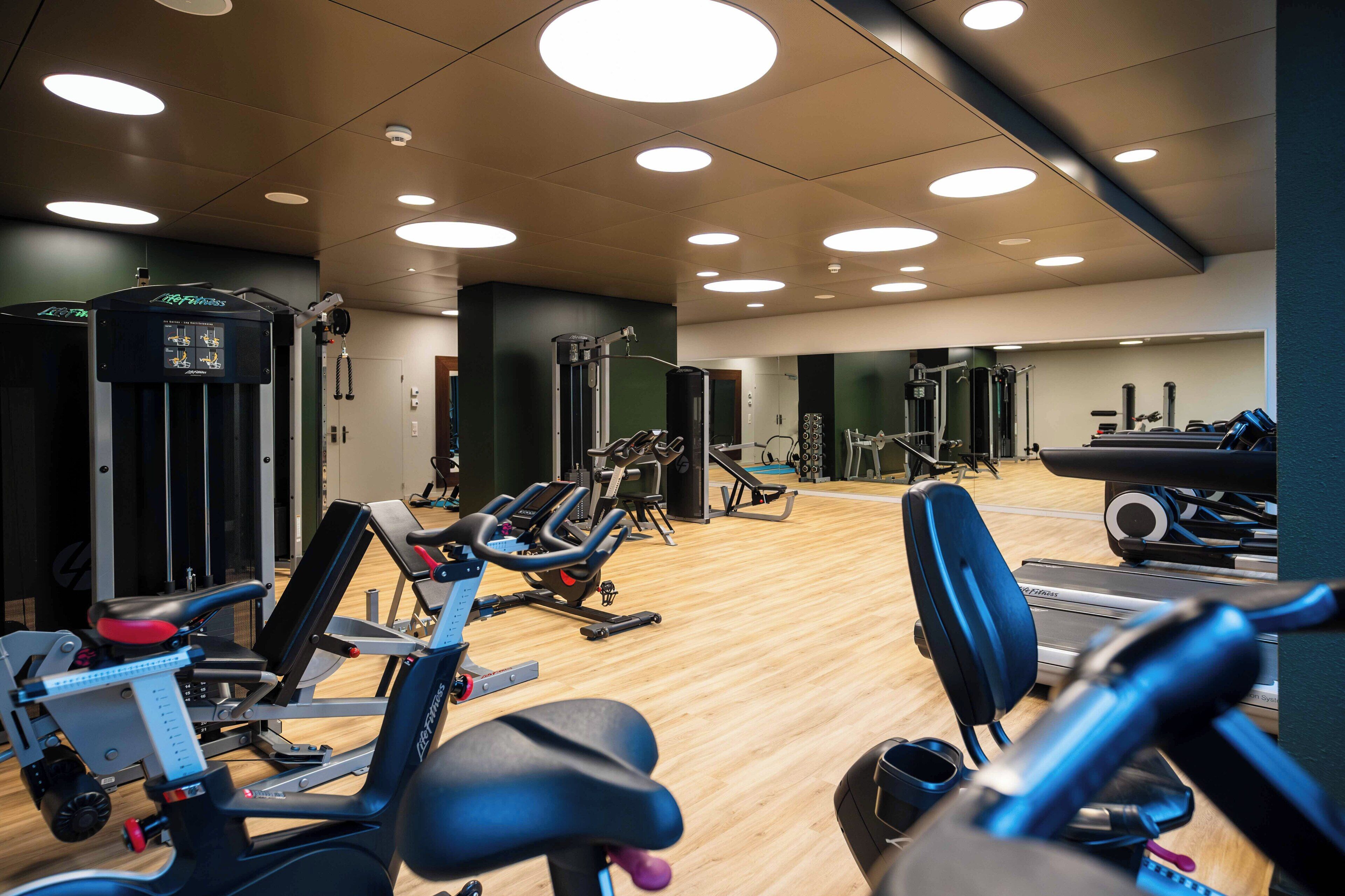 A gym with various exercise equipment, including treadmills, stationary bikes, and weight machines.