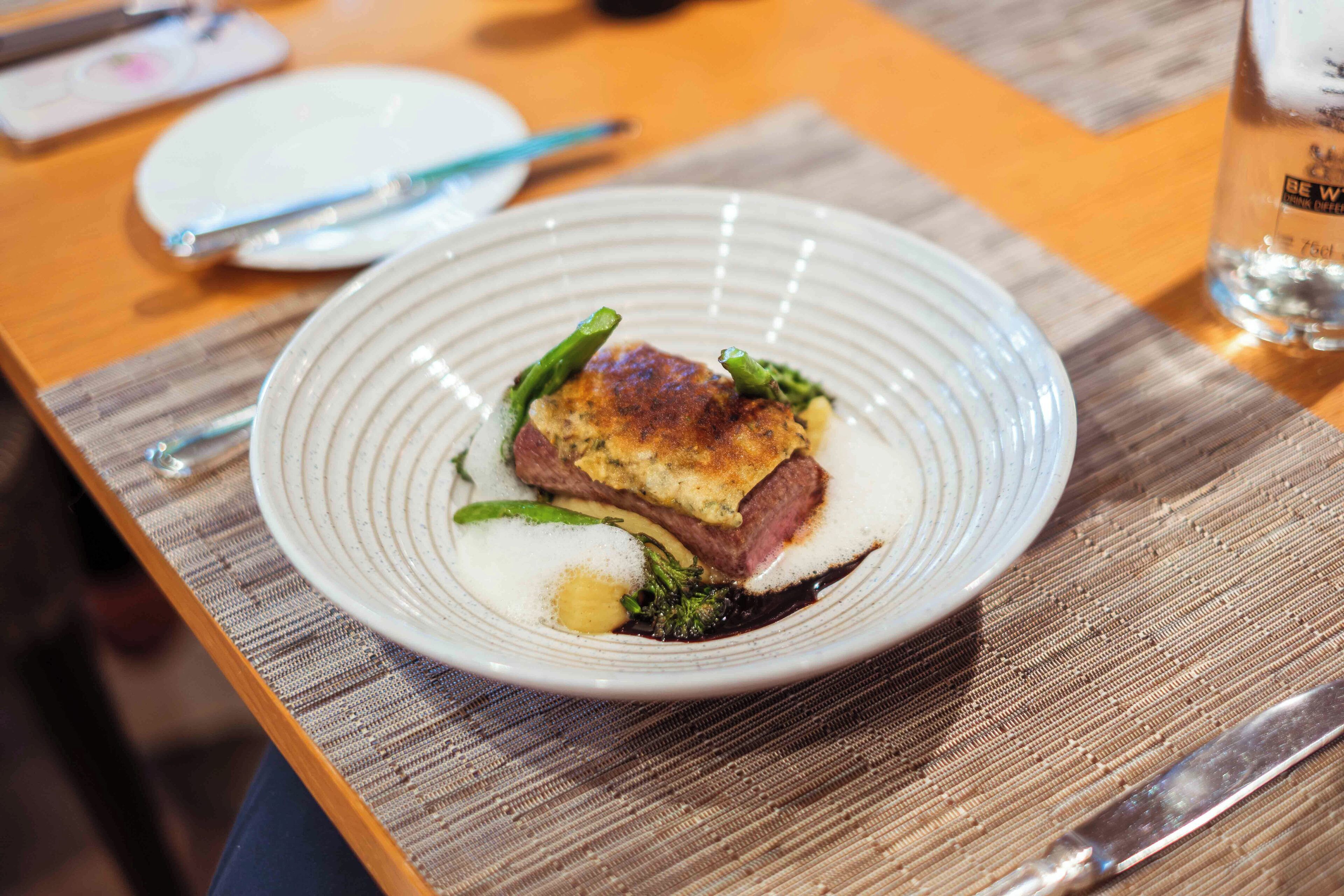 Un plato de comida sobre una mesa de madera, con un cuchillo y un vaso de agua cerca.