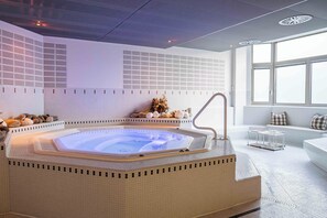 A modern spa room with a hot tub, a seating area with a view, and a decorative wall. - Hotel Seepark Thun (Thun)