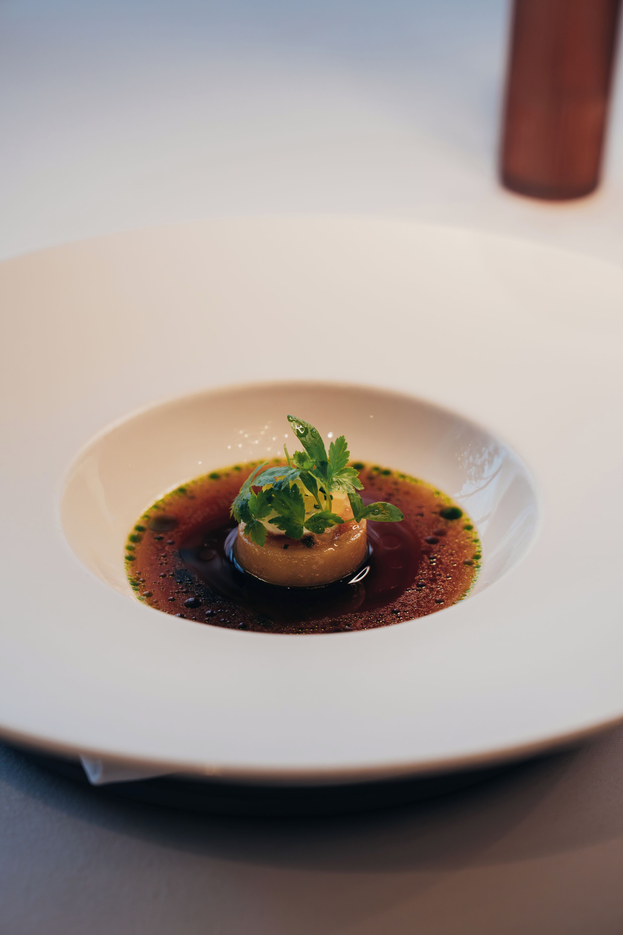 A white plate with a dish centered on it, surrounded by a dark sauce.