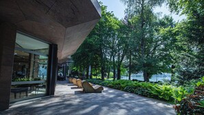 A pathway with benches, surrounded by lush greenery and a body of water in the background. - Hotel Seepark Thun (Thun)