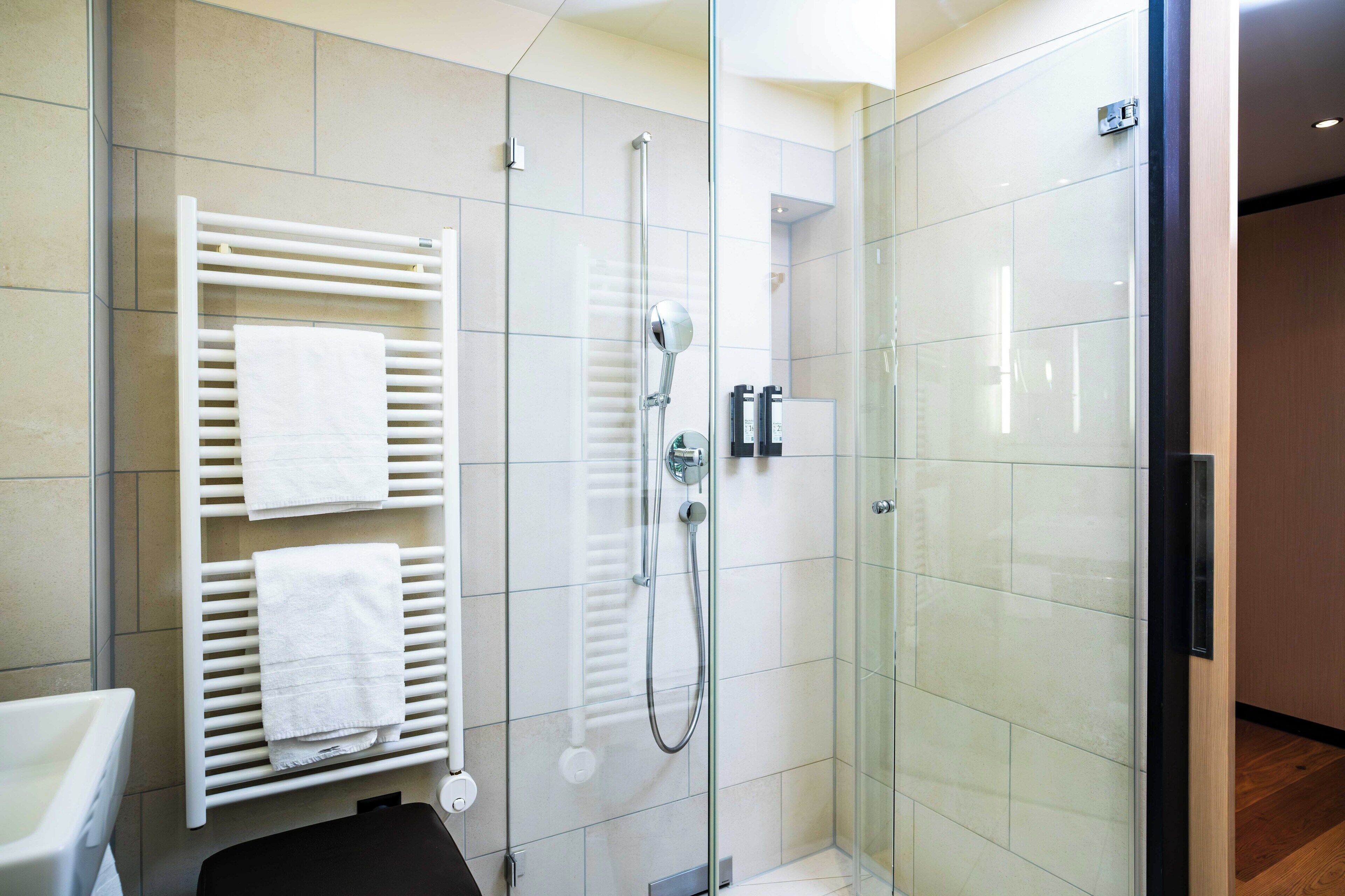 Ein modernes Badezimmer mit Duschkabine aus Glas, einem weißen Handtuchhalter und einer sichtbaren Toilette.