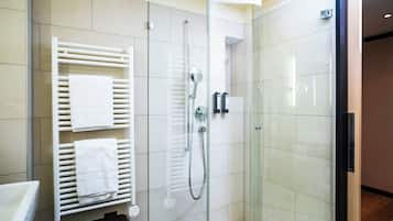 Ein modernes Badezimmer mit Duschkabine aus Glas, einem weißen Handtuchhalter und einer sichtbaren Toilette.