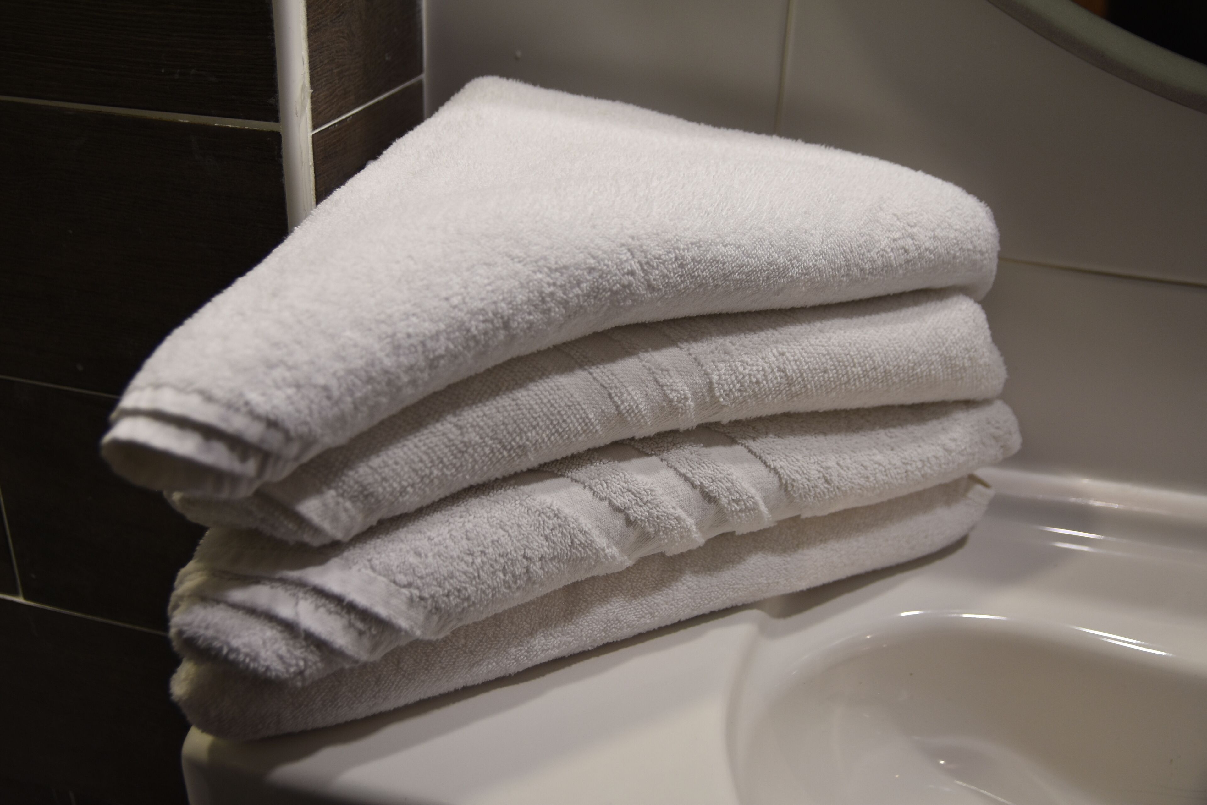 Une pile de serviettes blanches sur un lavabo blanc dans la salle de bain.
