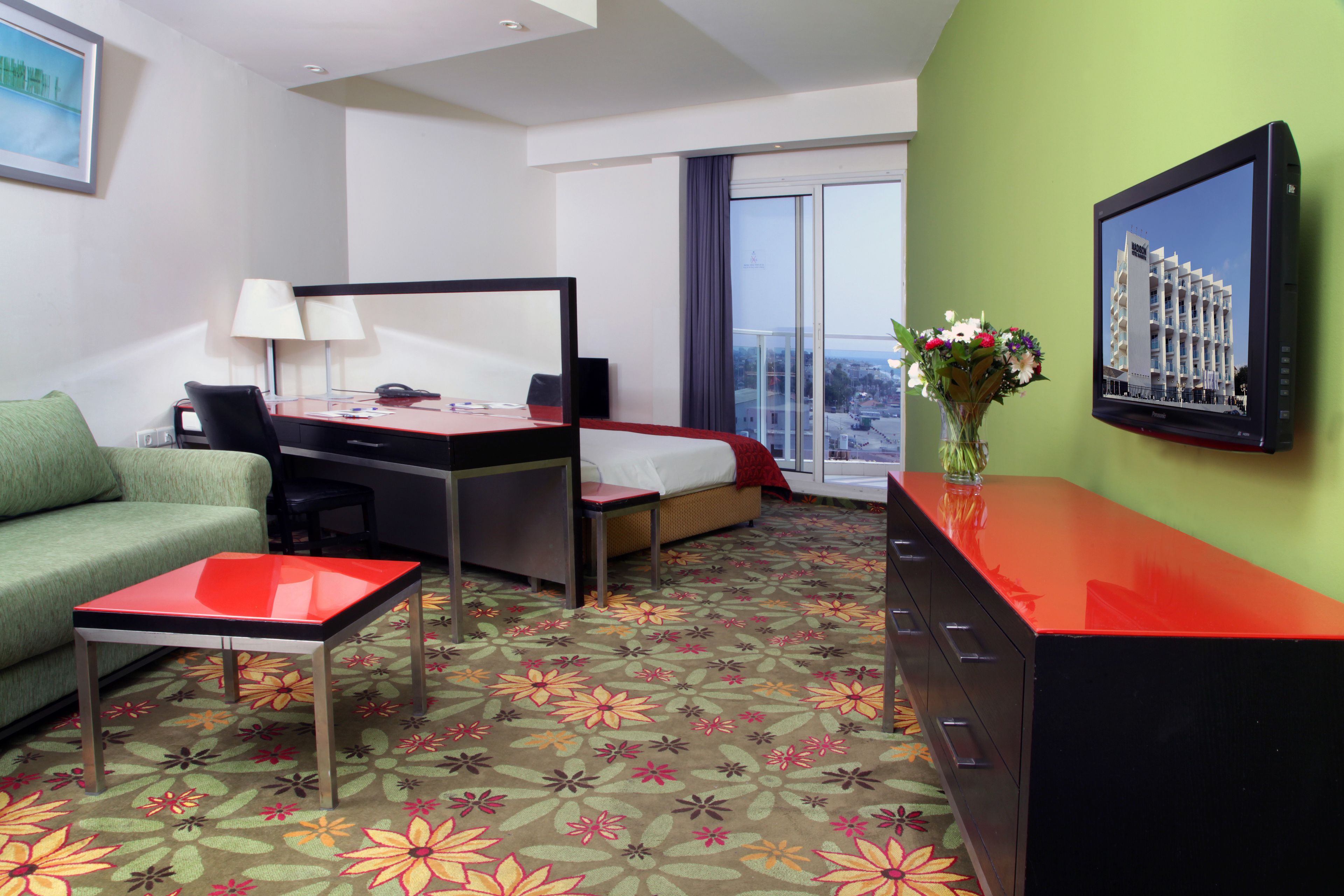 A hotel room with a bed, desk, and green sofa.