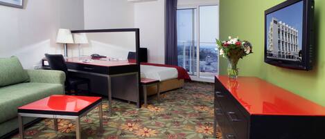 A hotel room with a bed, desk, and green sofa.