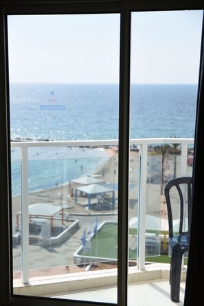 Un balcón con vista al mar, una zona de piscina y una silla.