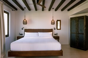 A large bed with a wooden headboard, two bedside tables, a ceiling fan, and a wardrobe. - Casa Maca Hotel (Ibiza Town)