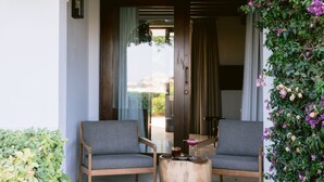 An outdoor seating area with two chairs and a round table, surrounded by lush greenery and purple flowers. - Casa Maca Hotel (Ibiza Town)