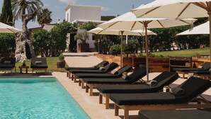 A poolside area with lounge chairs and umbrellas, a clear pool, and a landscaped garden with trees and shrubs. - Casa Maca Hotel (Ibiza Town)
