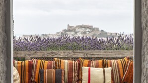 A cozy outdoor seating area with a bench and cushions, overlooking a field of lavender and a distant building. - Casa Maca Hotel (Ibiza Town)