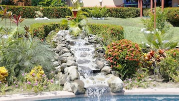 Una piscina al aire libre, sombrillas, sillones reclinables de piscina