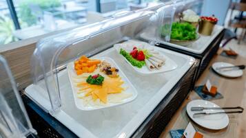 A buffet with various food items including cheese, fruits, and vegetables.