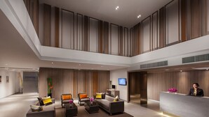 Eine geräumige Lobby mit Empfangsschalter, Sitzgelegenheiten und einer hohen Decke mit Holzverkleidung.