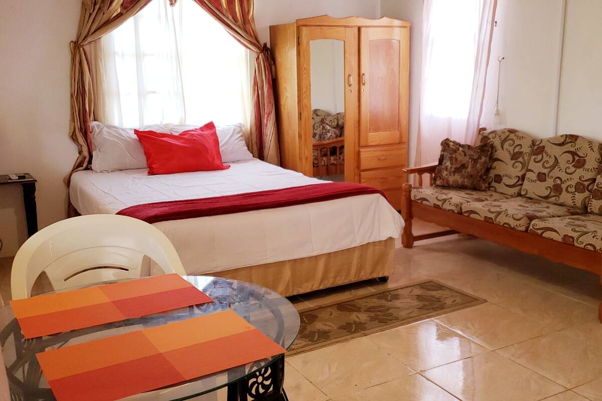 Une chambre à coucher comprenant un lit, une armoire en bois, un canapé, une table ronde et une chaise.