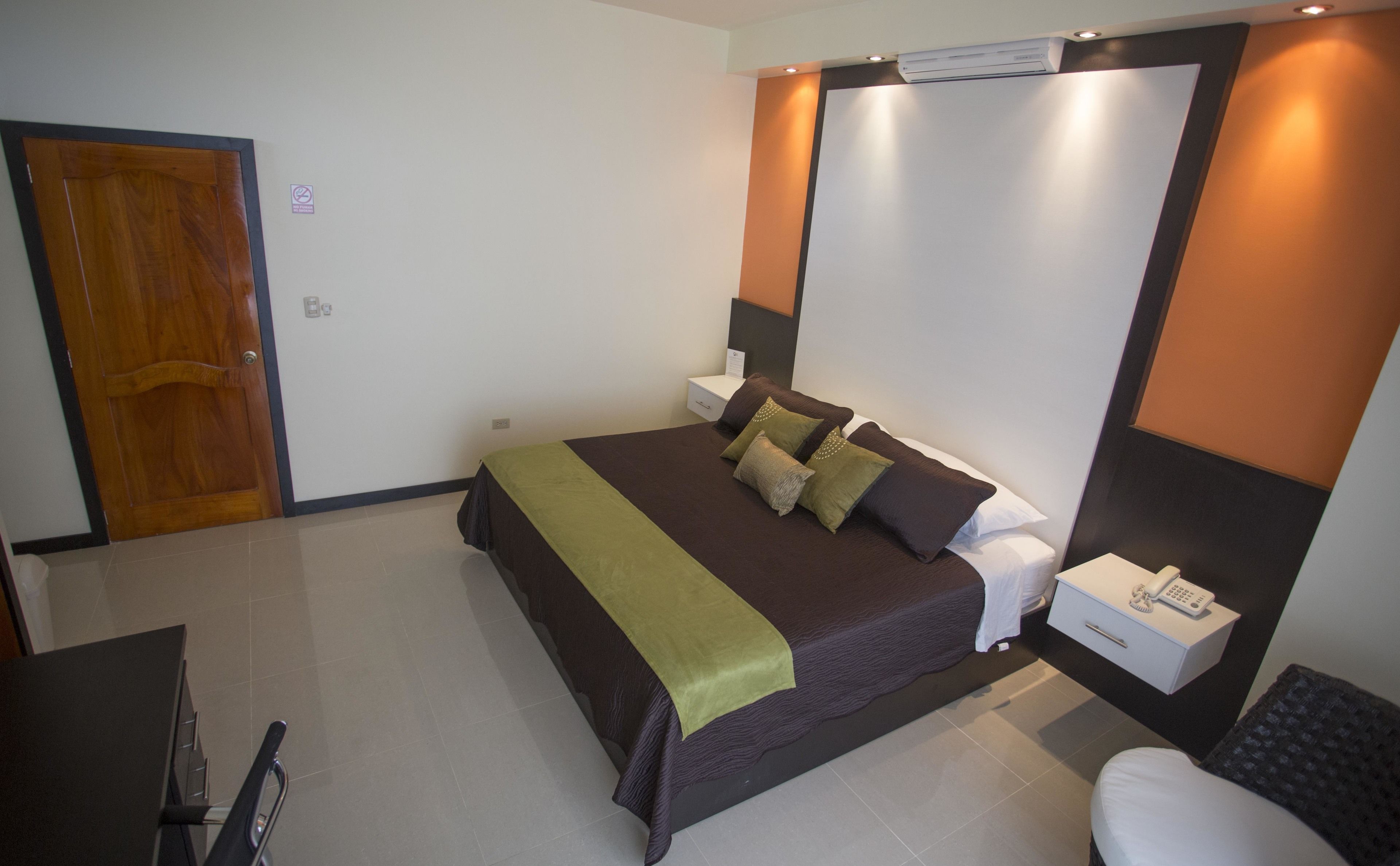 Una habitación de hotel con una cama, mesitas de noche, un escritorio y una silla.