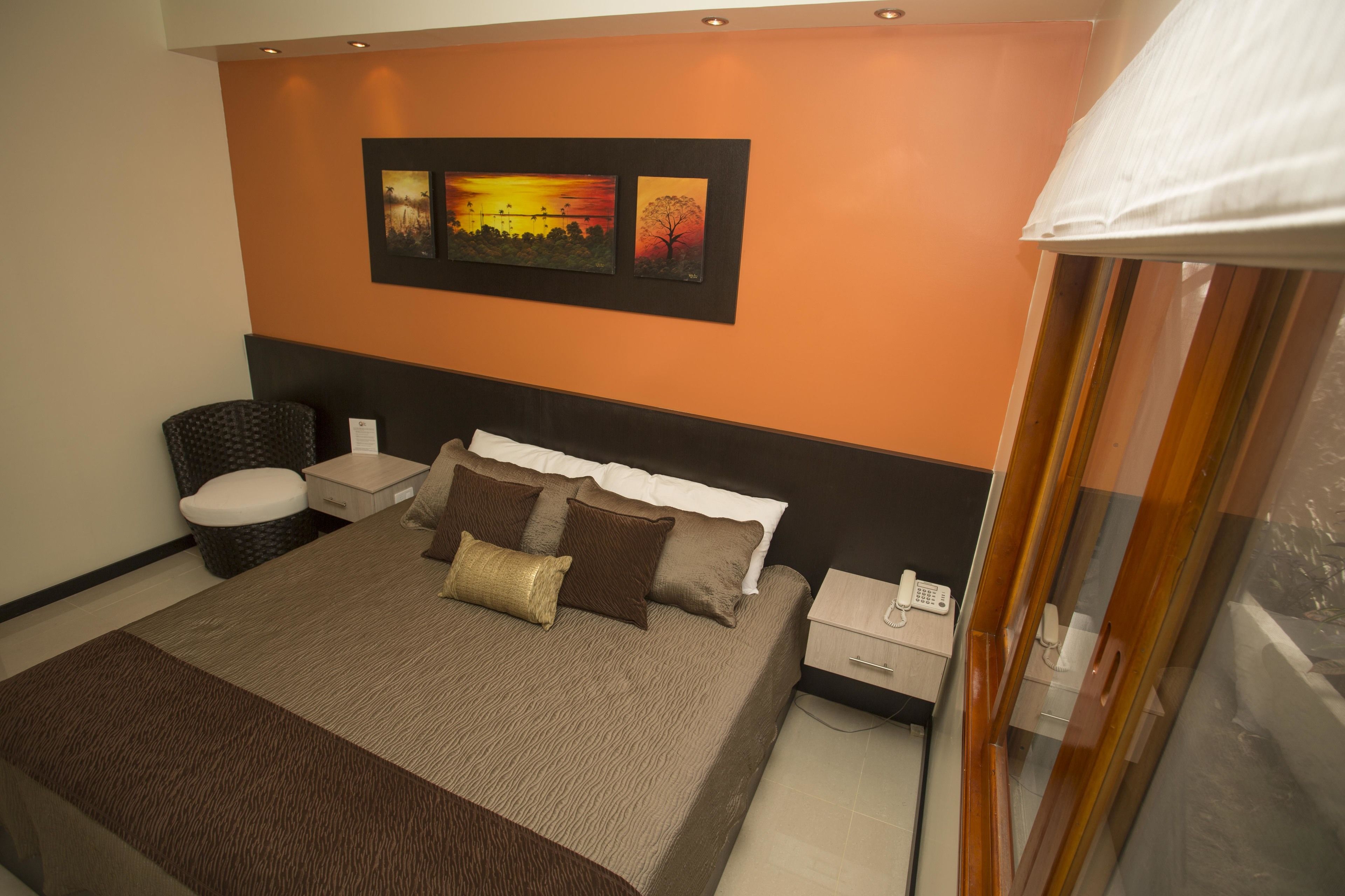 Ein modernes Hotelzimmer mit einem großen Bett, einem Nachttisch, einem Sessel und einem Beistelltisch.