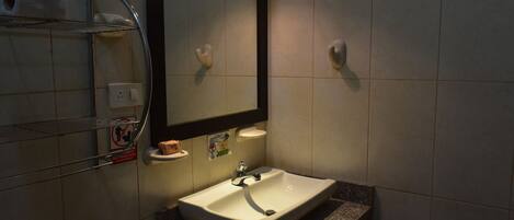 Un baño con lavabo, espejo, toallero y dispensador de jabón.