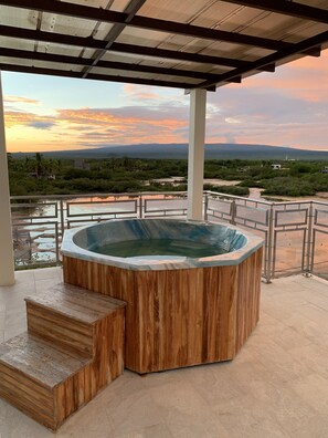 A hot tub with wooden steps and a view of a landscape with greenery and distant mountains. - Hotel La Laguna Galapagos (Puerto Villamil)