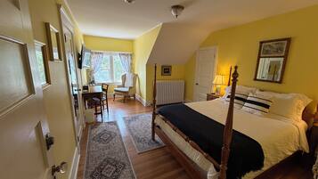 A bedroom with a four-poster bed, a desk, and a chair.