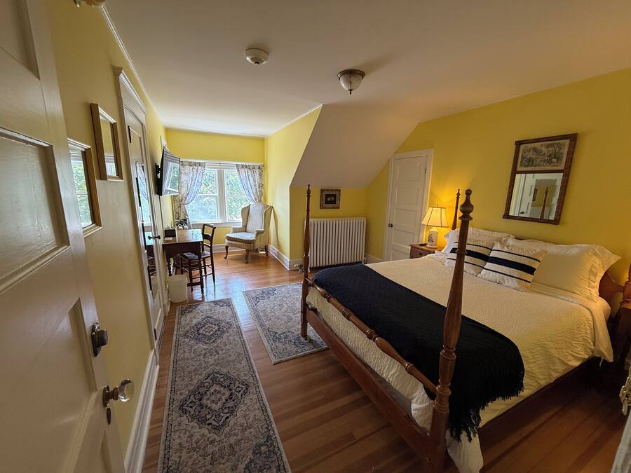 A bedroom with a four-poster bed, a desk, and a chair.