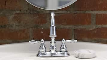 A white bathroom sink with a chrome faucet and a round mirror above it.