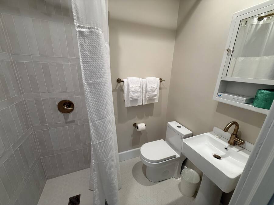 Een badkamer met douche, toilet, wastafel en handdoekhouder.