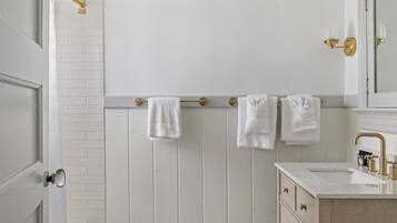 A bathroom with a white bathtub, a wooden vanity with a sink, and a mirror above the vanity.