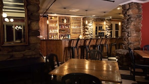 Un restaurante con barra de pared de piedra, mesas y sillas de madera.