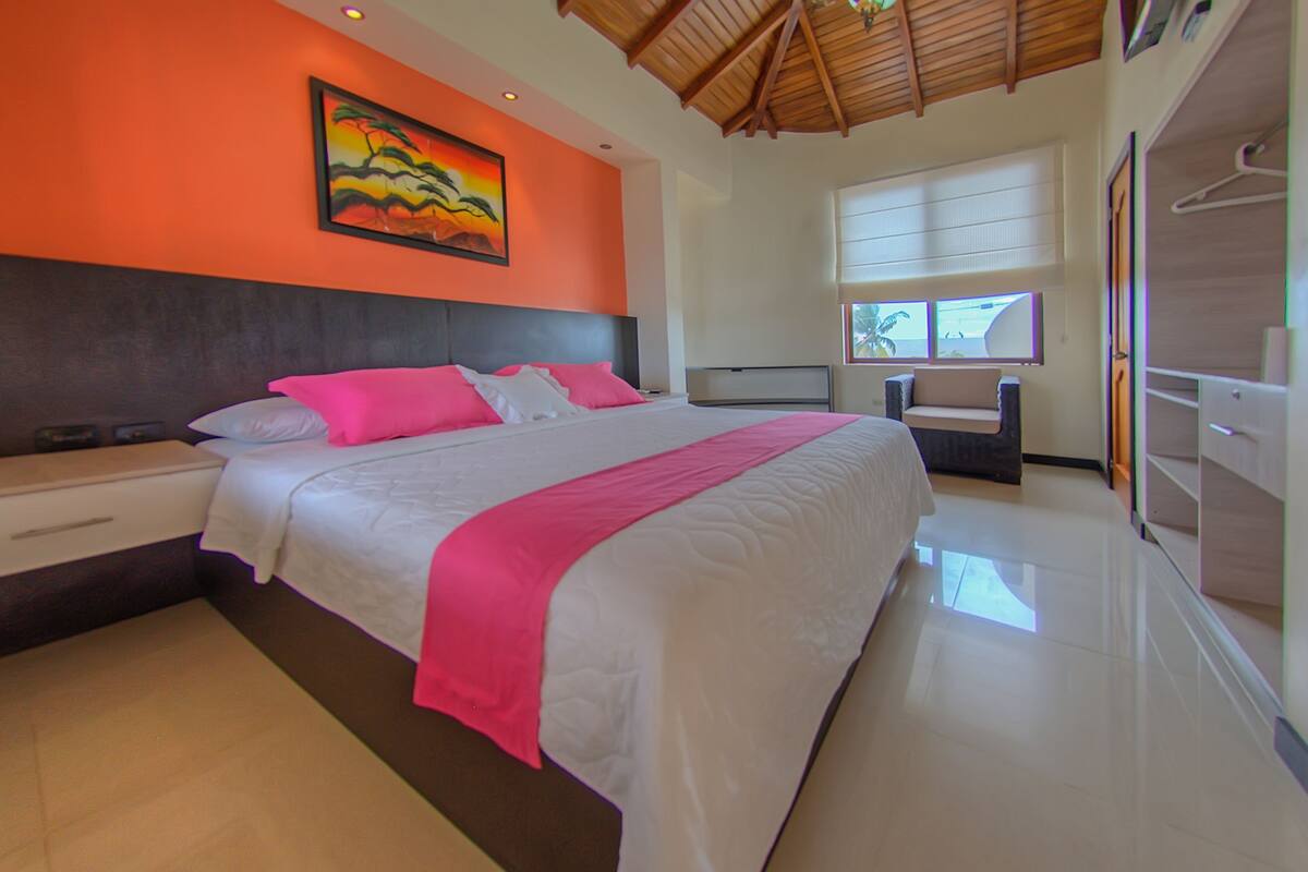 Un dormitorio moderno con una cama grande, una mesita de noche, un aparador y un cuadro en la pared.